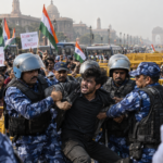 Security officers detain a protester during Cockroach Janta Party demonstrations in New Delhi