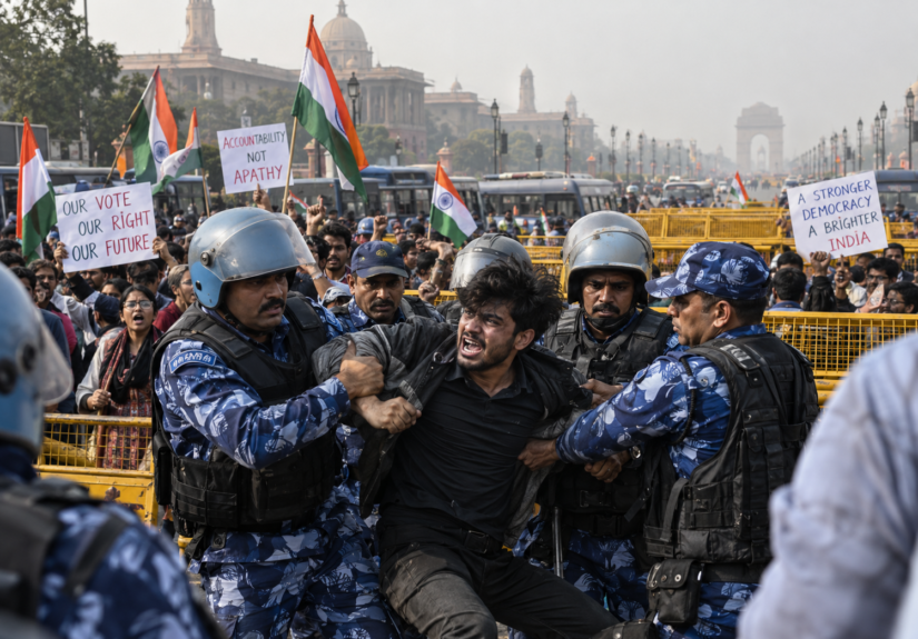 Security officers detain a protester during Cockroach Janta Party demonstrations in New Delhi